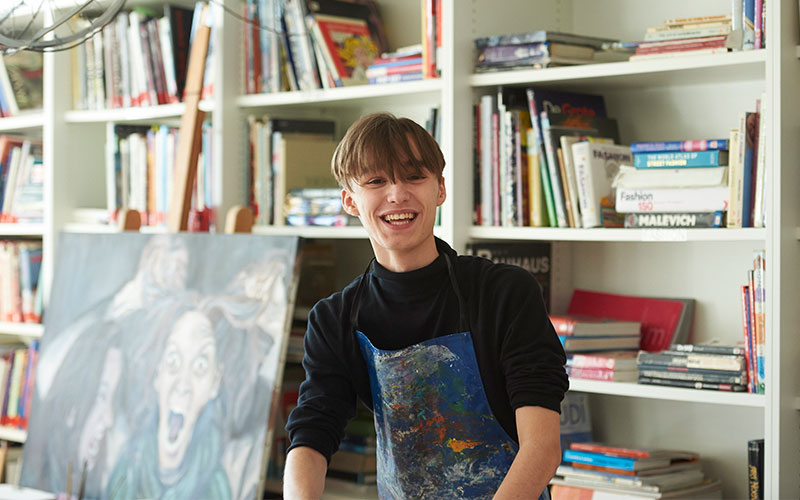 Senior School male art student standing in front of painting